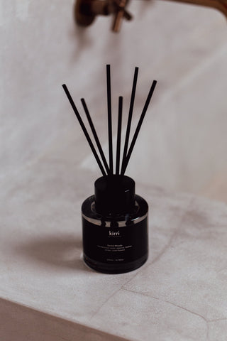 kirri reed diffuser with black reeds on a stone bench