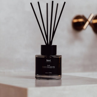 kirri bondi reed diffuser with black reeds beside a brass tap